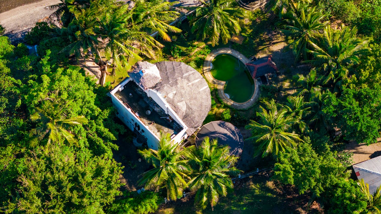 Aerial shot of a tropical beach house surrounded by palm trees in Bacong, Philippines.